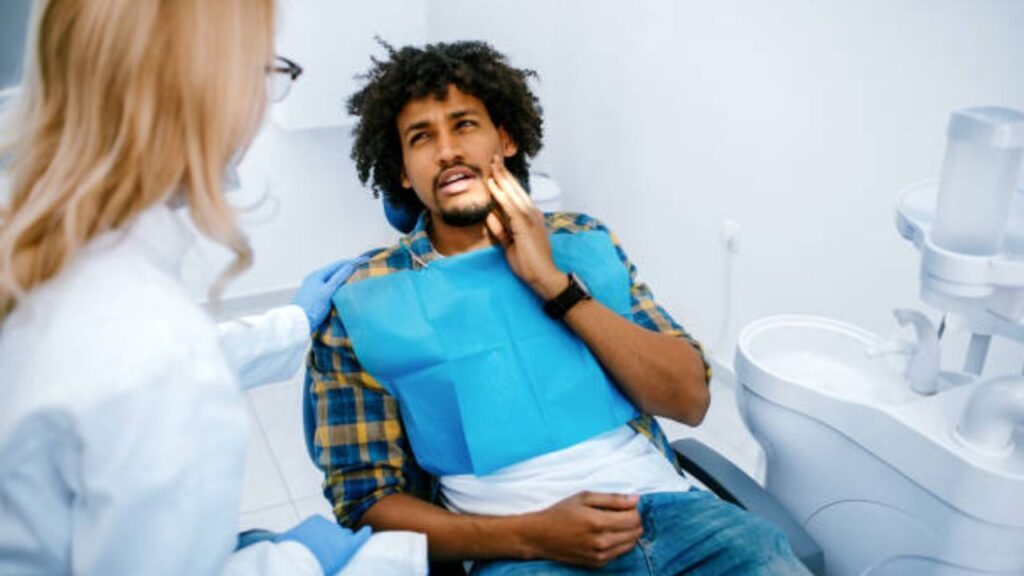 homem relatando a dentista um sintoma de sobremordida